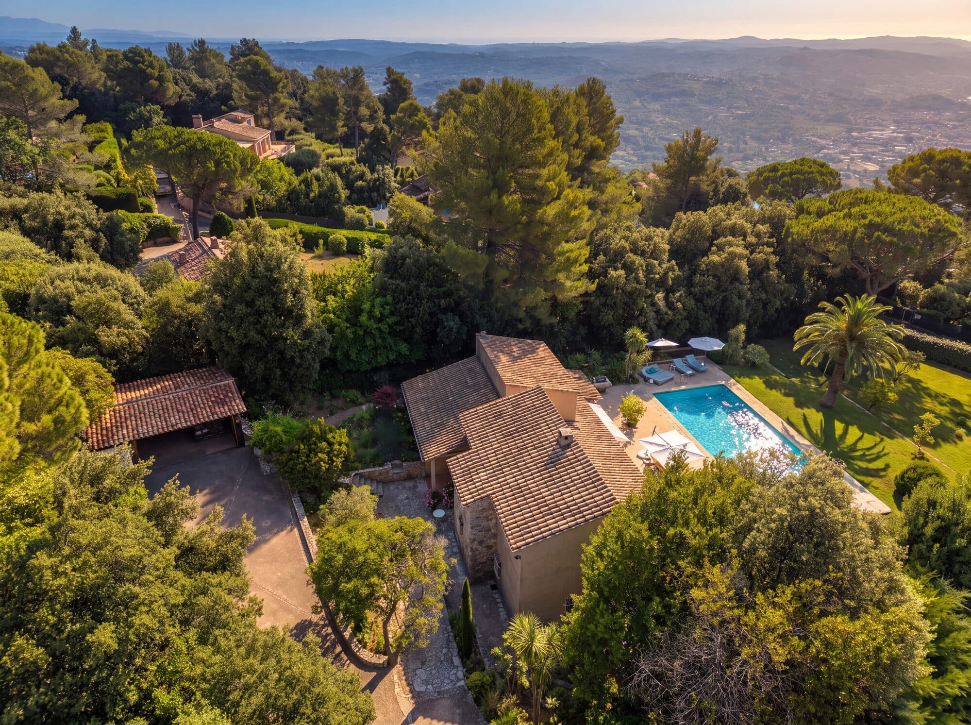 Aerial view of tiled roofs, a pool and a garden set among the trees