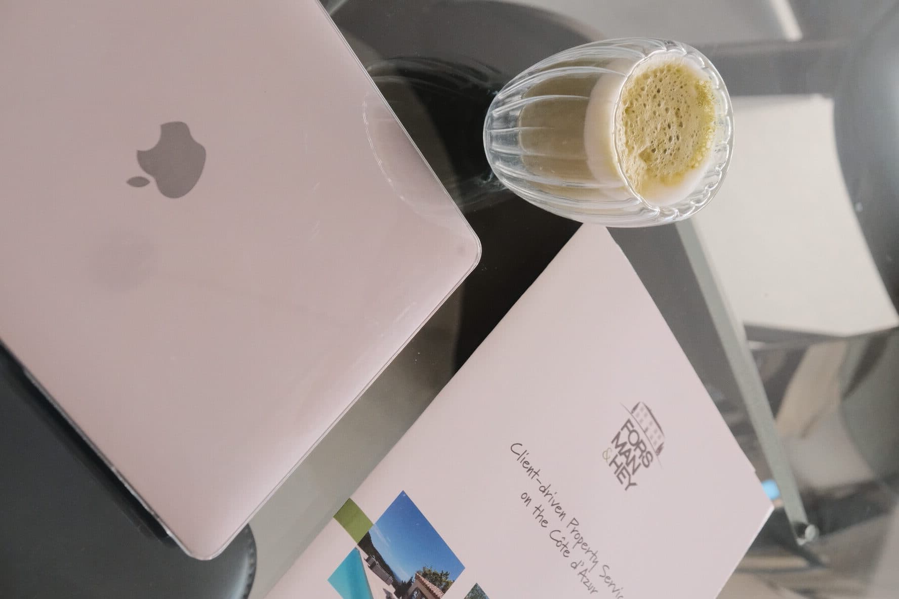 The agency brochure beside a laptop on a glass table