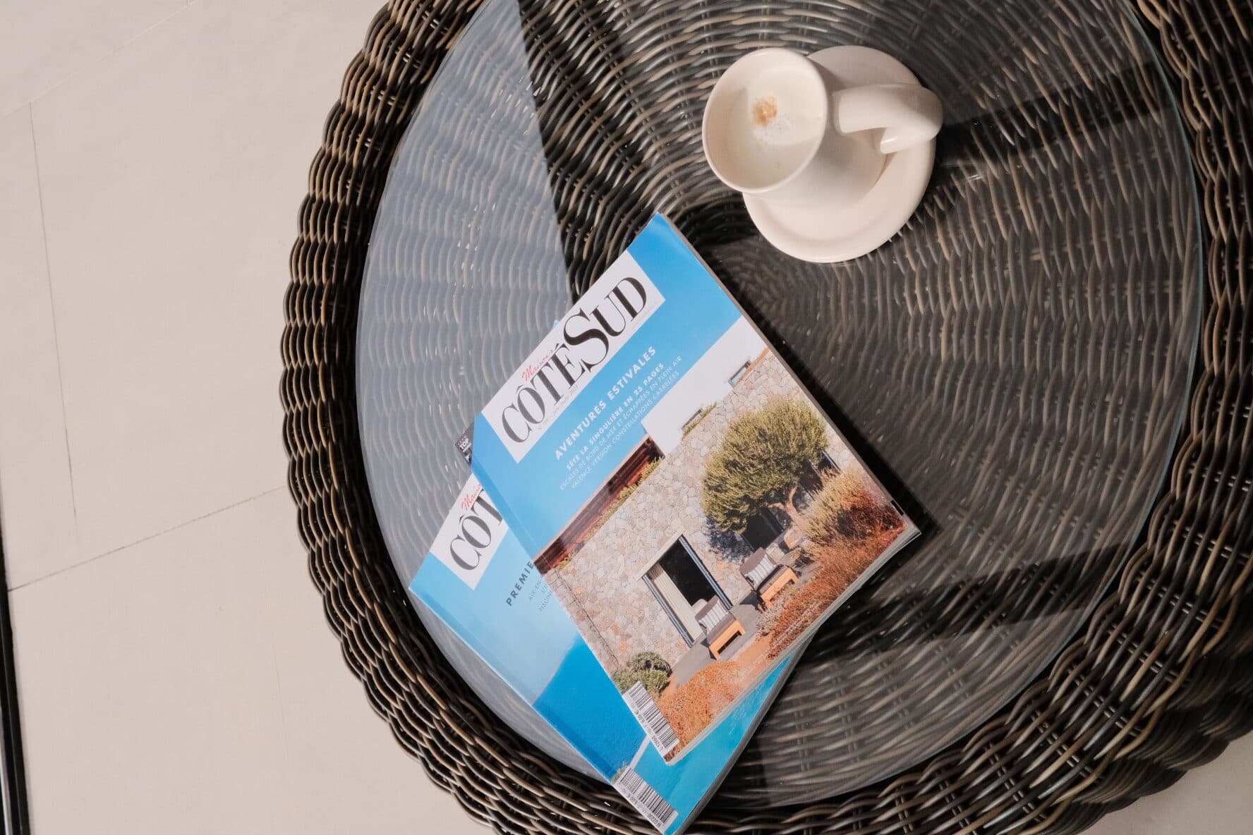 Provençal interiors magazines laid out on a rattan coffee table