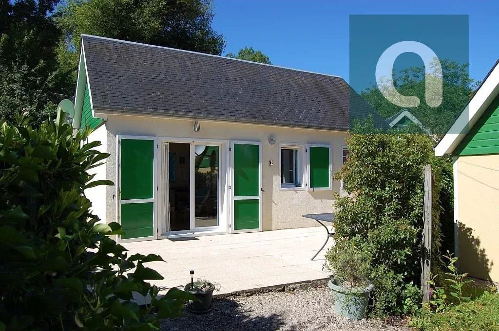 Maison de campagne avec volets verts et jardin.
